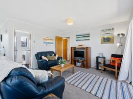 A living room with a sofa, coffee table, and television at Kapiti Breeze - Waikanae Beach Holiday Home