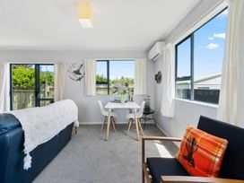 A living room with a sofa and dining area at Kapiti Breeze - Waikanae Beach Holiday Home