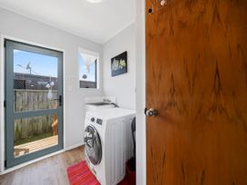 A laundry room with a washing machine and a door leading outside at Kapiti Breeze - Waikanae Beach Holiday Home