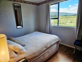 A bedroom with a bed and window at Restful on Rutherford - Waikanae Beach
