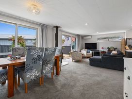 A living room with a dining table and chairs next to a sofa and television at Rotorua Holiday Home in Rotorua