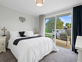 A bedroom with a bed and window overlooking a deck at Rotorua Holiday Home in Rotorua