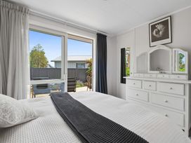 A bedroom with a bed, dresser, and window at Rotorua Holiday Home in Rotorua