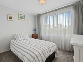 A bedroom with a bed, curtains, and a nightstand at Rotorua Holiday Home in Rotorua