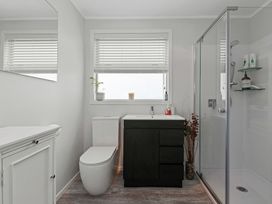 A bathroom with a toilet, sink, shower and window at Rotorua Holiday Home in Rotorua