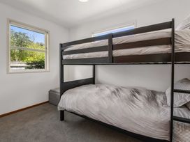 A bedroom with a bunk bed and windows at Lake Okareka Holiday Home in Rotorua
