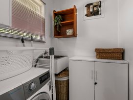 A laundry room with a washing machine and storage cabinet at Lake Okareka Holiday Home Rotorua