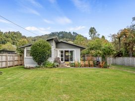 A house with lawn and deck chairs at Lake Okareka Holiday Home Rotorua