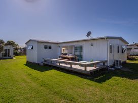 A house with a deck and table at Whangamata