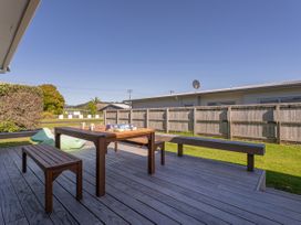 A wooden table and bench on a deck in an outdoor area at Whangamata
