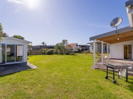 A garden with grass and a patio at Whangamata