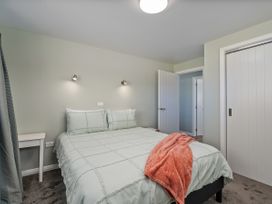 A bedroom with a bed and side table at Whangamata