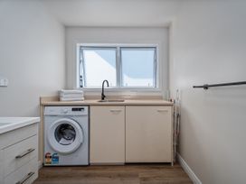 A laundry room with a washing machine and sink at Whangamata