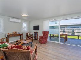 A living room with furniture and sliding door at Whangamata