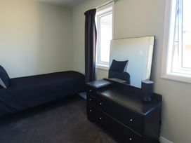 A bedroom with a bed and dresser at Caddy's Shack - Whangamata