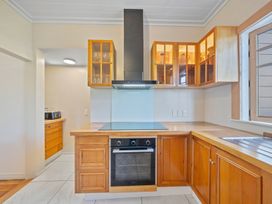 A kitchen with wooden cabinets and a stove at Ocean Breeze Cottage - Paekakariki Holiday Home