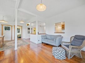 A living room with a sofa and armchair at Ocean Breeze Cottage - Paekakariki Holiday Home