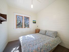 A bedroom with a bed, window, and nightstand at Ocean Breeze Cottage - Paekakariki Holiday Home