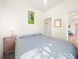 A bedroom with a bed and bedside table at Ocean Breeze Cottage - Paekakariki Holiday Home