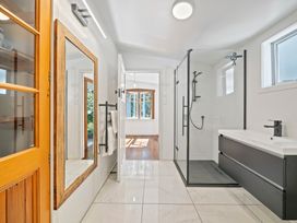 A bathroom with a shower, vanity, and mirror at Ocean Breeze Cottage - Paekakariki Holiday Home