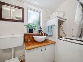 A bathroom with a sink a toilet and a laundry machine at Bellbird House - Paekakariki
