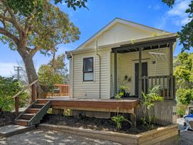 A house with a deck and surrounding greenery at Bellbird House - Paekakariki