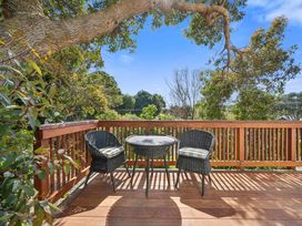 A deck with a table and chairs at Bellbird House - Paekakariki Holiday Home Paekakariki