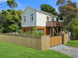 A house with a deck and fenced yard at Bellbird House - Paekakariki