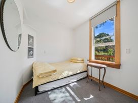 A bedroom with a bed and a window at Bellbird House - Paekakariki