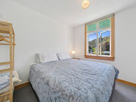 A bedroom with a bed and window at Bellbird House - Paekakariki