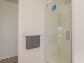 A bathroom with a shower and towel rack at Bailey's Bach - Whitianga Holiday Home Whitianga