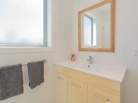 A bathroom with a sink and mirror at Bailey's Bach - Whitianga Holiday Home