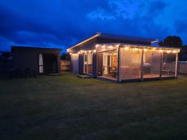 A house with outdoor lights and a shed at Bailey Bach - Whitianga Holiday Cabin in Whitianga