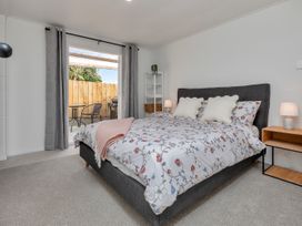 A bedroom with a bed and sliding door leading to outdoor seating at Whangarei in Whangarei