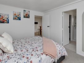 A bedroom featuring a bed with floral bedding and artwork on the walls at Whangarei