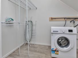 A laundry room with a washing machine and ironing board at Whangarei
