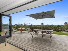 An outdoor deck with a table and chairs at Home Away From Home - Ruakaka