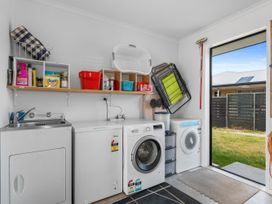 A laundry room with a washing machine and drying rack at Home Away From Home - Ruakaka