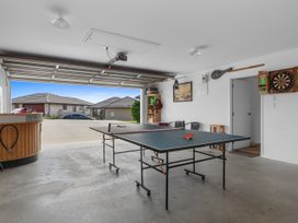 A garage with a ping pong table and dartboard at Home Away From Home - Ruakaka