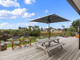 A deck with a table and chairs beside a pond at Home Away From Home - Ruakaka