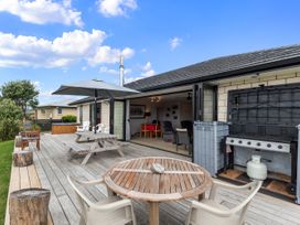 A deck with a table and chairs leading to a barbecue at Home Away From Home - Ruakaka