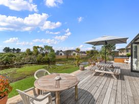A deck area with table and chairs overlooking a pond at Home Away From Home - Ruakaka