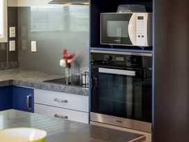 A kitchen with a microwave, oven, sink and flower vase at Lake Taupo Holiday Home, Lake Taupo