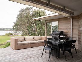 An outdoor patio with a couch and dining set at Tranquil Waterfront Getaway - Point Wells Warkworth