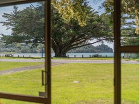 A view of a large tree and water from a window at Whitianga Holiday Home in Whitianga