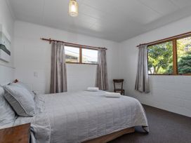A bedroom with a bed and chair at Whitianga Holiday Home in Whitianga