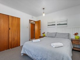 A bedroom with a bed and side tables at Whitianga Holiday Home in Whitianga