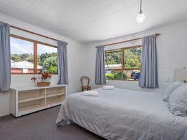 A bedroom with a bed and shelves at Whitianga Holiday Home in Whitianga