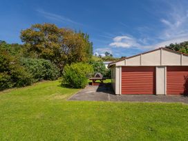 A garden with a building and tree at Whitianga Holiday Home Whitianga