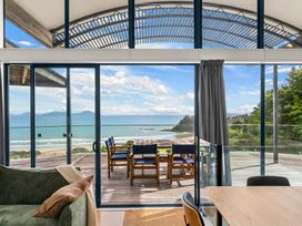 A living room with a sliding glass door and view of the ocean at Langscape - Langs Beach Holiday Home Langs Beach